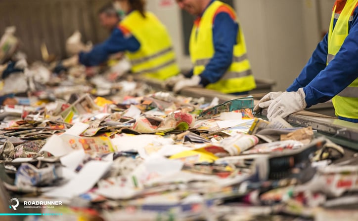 recycling center workers sorts recycling on a conveyor belt