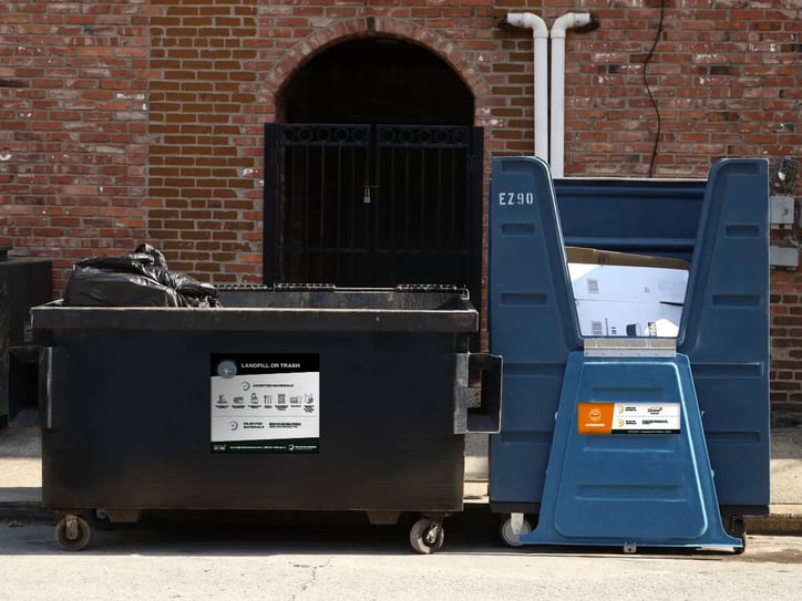 a dumpster and a crate full of cardboard