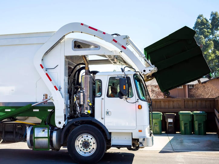 a garbage truck picking up a dumpster